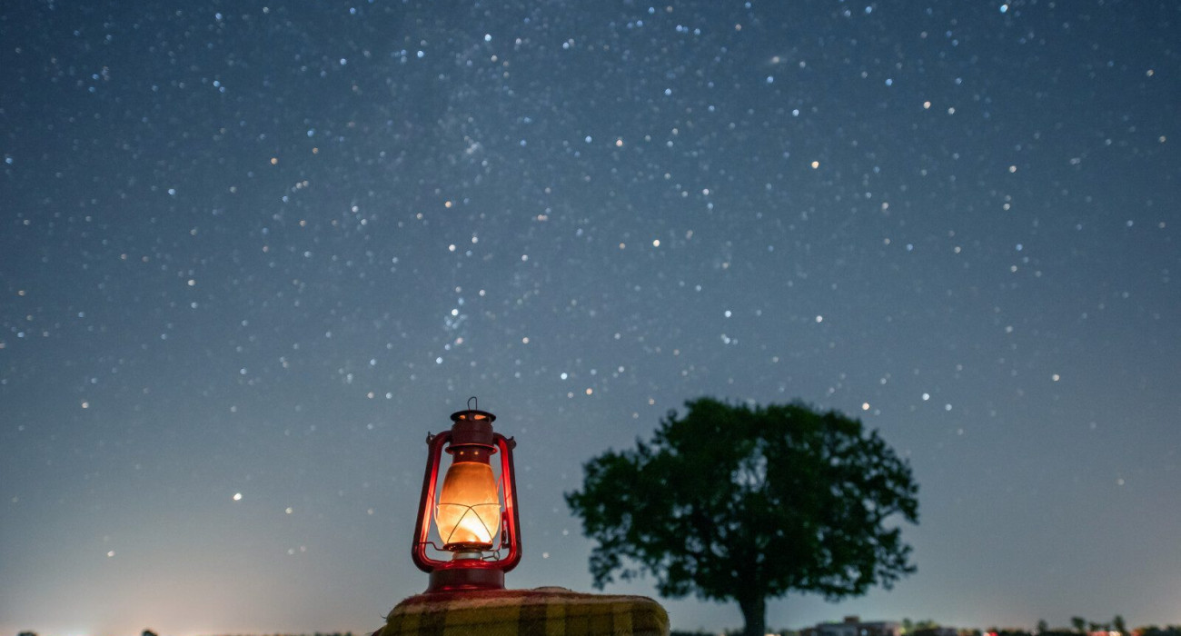 old red petrol lamp on a cozy blanket. a sky full of stars. bokeh milky way. long exposure photography. clear night. light trails. cozy autumn and winter background.